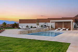 Pool at dusk with outdoor lounge area, a patio area, an outdoor pool, and a mountain view