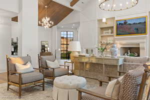 Living room with a chandelier, high vaulted ceiling, built in features, beamed ceiling, and wood finished floors