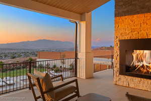 Balcony featuring an outdoor stone fireplace and a mountain view