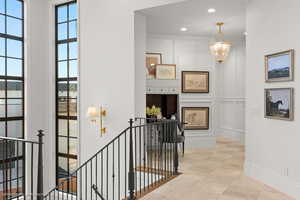 Hall with an upstairs landing, a decorative wall, recessed lighting, and a chandelier