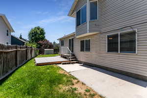Fenced backyard featuring a wooden deck and a patio area
