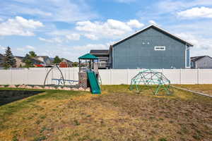 Fenced backyard featuring a playground