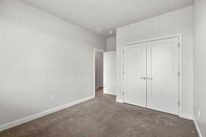 Unfurnished bedroom featuring carpet flooring and a closet