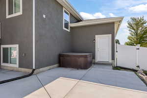 Property entrance featuring a hot tub, a patio area, and stucco siding