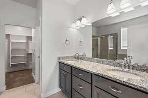 Full bathroom featuring a stall shower, a spacious closet, double vanity, and tile patterned flooring