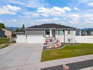 View of front of house with a garage, concrete driveway, a residential view, a mountain view, and stone siding