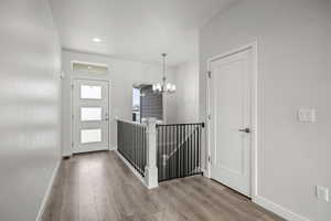 Foyer featuring wood finished floors, a chandelier, and recessed lighting