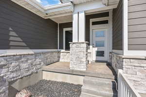 View of exterior entry with a porch and stone siding
