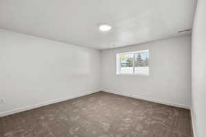 Carpeted spare room featuring baseboards