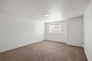 Empty room featuring light carpet and a textured ceiling