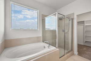 Full bathroom with a bath, a stall shower, a walk in closet, and tile patterned flooring