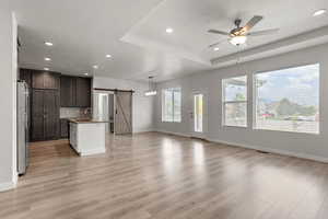 Kitchen with a barn door, recessed lighting, open floor plan, dark brown cabinetry, and a ceiling fan