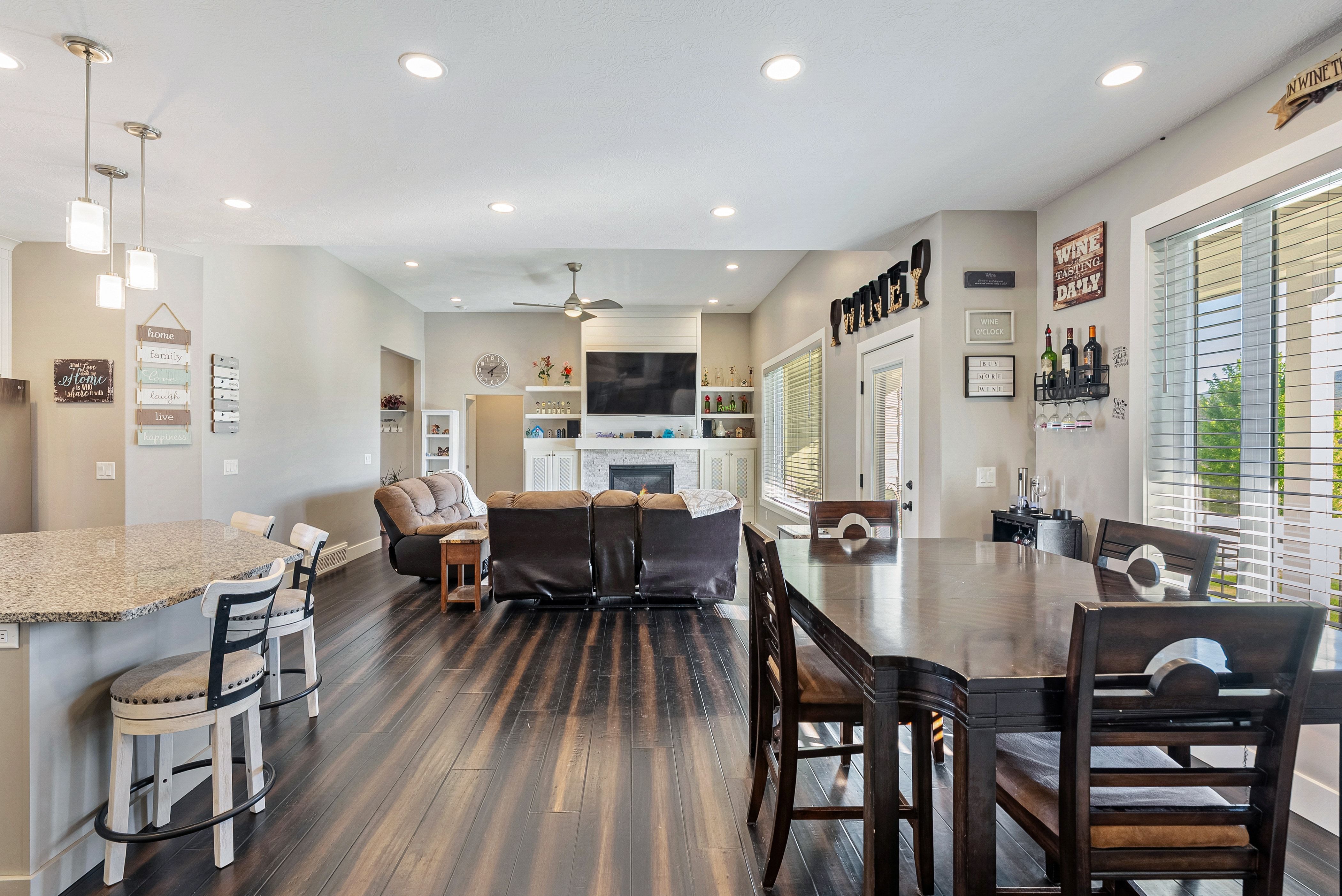 Open-concept living space featuring wood-finish flooring, recessed lighting, and a white stone fireplace with built-in shelving