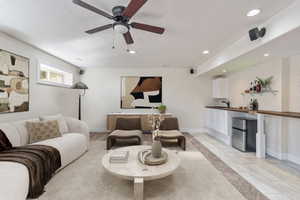 Bright living space featuring a ceiling fan, recessed lighting, and a built-in wet bar with a stainless steel mini-fridge