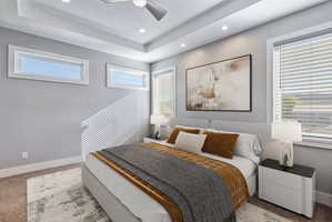Spacious bedroom featuring a tray ceiling with recessed lighting and a ceiling fan