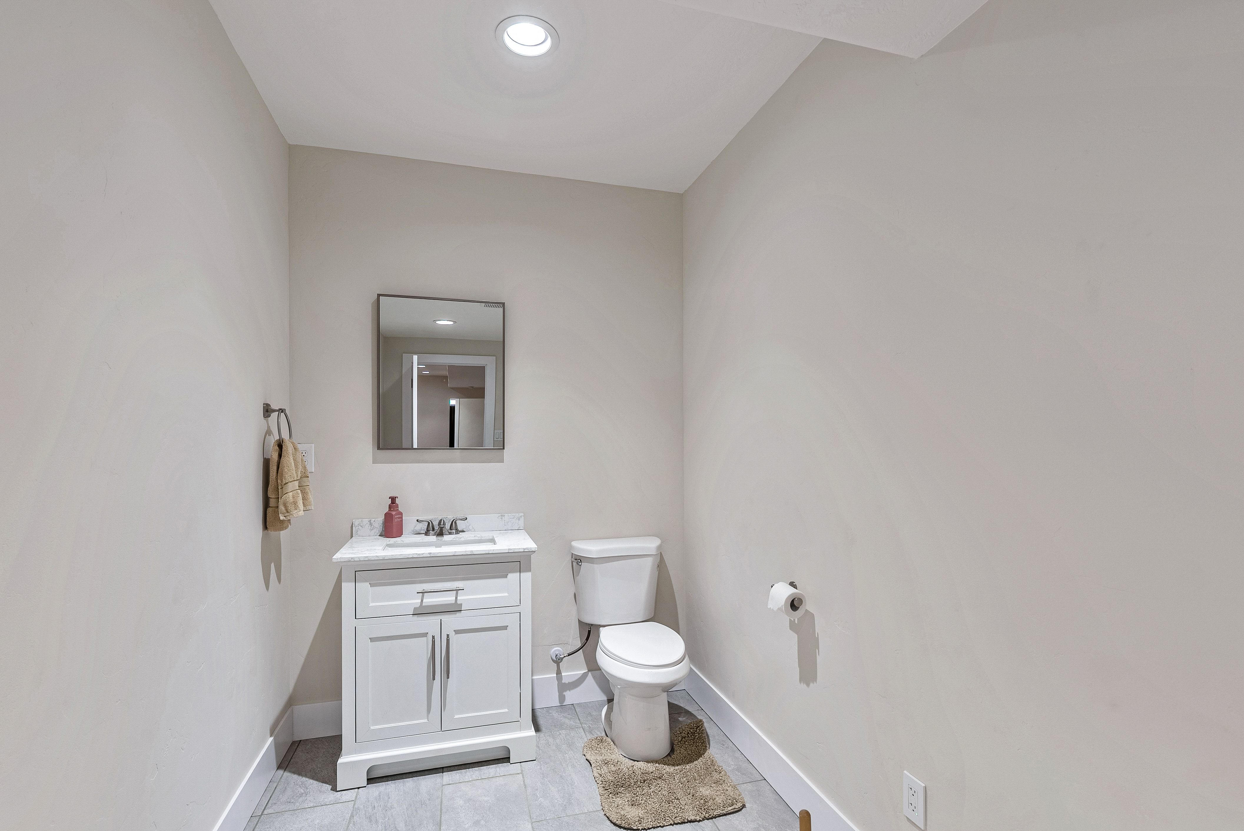 Powder room featuring a white single vanity with a stone countertop, an undermount sink, and a rectangular mirror