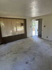 Spare room featuring arched walkways and a textured ceiling