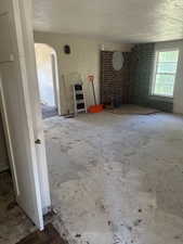 Unfurnished living room with arched walkways and a textured ceiling