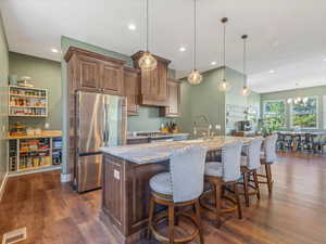 Kitchen featuring freestanding refrigerator, light stone countertops, dark wood-style flooring, pendant lighting, and recessed lighting