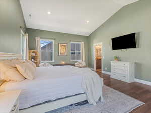 Bedroom featuring vaulted ceiling, dark wood finished floors, recessed lighting, and ensuite bathroom