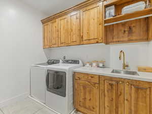 Washroom with cabinet space, washing machine and dryer, and light tile patterned floors