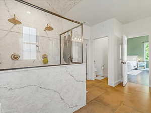Full bathroom with a marble finish shower and tile patterned floors
