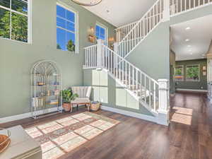 Living room featuring wood finished floors, stairway, recessed lighting, and a high ceiling