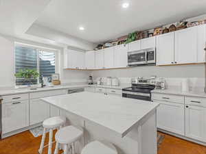 Kitchen featuring appliances with stainless steel finishes, a breakfast bar, recessed lighting, a center island, and white cabinetry
