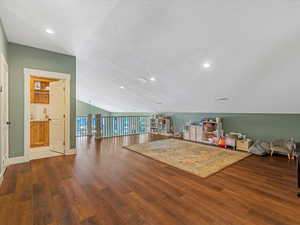 Interior space with wood finished floors, lofted ceiling, recessed lighting, and a textured ceiling