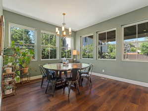 Dining room with a chandelier, plenty of natural light, and dark wood-type flooring