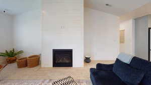 Living area with carpet flooring and a large fireplace