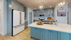 Kitchen featuring premium appliances, a chandelier, light wood-style floors, light countertops, and recessed lighting