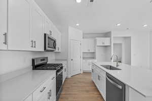 Kitchen featuring appliances with stainless steel finishes, white cabinets, recessed lighting, light wood-style flooring, and light countertops