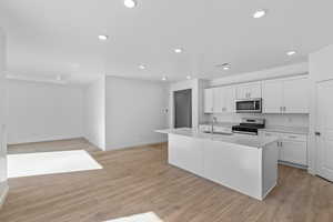 Kitchen featuring recessed lighting, appliances with stainless steel finishes, white cabinetry, light countertops, and light wood-style floors