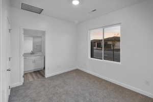Unfurnished bedroom with carpet floors and ensuite bathroom