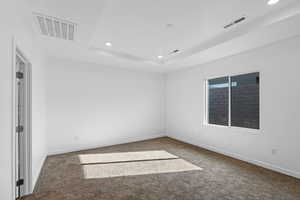 Carpeted empty room featuring recessed lighting and a tray ceiling