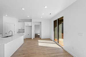 Kitchen featuring white cabinetry, light countertops, recessed lighting, light wood-style flooring, and an island with sink