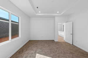 Unfurnished bedroom with carpet floors, recessed lighting, and a raised ceiling