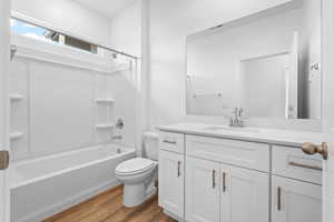 Bathroom with wood finished floors, vanity, and shower / bathtub combination