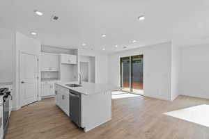 Kitchen featuring white cabinetry, light wood-style flooring, a center island with sink, black / electric stove, and recessed lighting