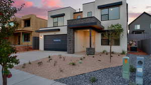 Contemporary house with stucco siding, driveway, an attached garage, and stone siding