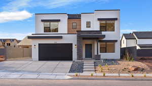 Contemporary house with stucco siding, an attached garage, concrete driveway, and stone siding