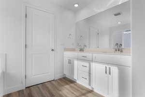 Bathroom featuring double vanity, wood finished floors, and recessed lighting