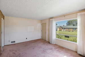 Unfurnished room featuring a textured ceiling and carpet floors