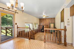 Stairs featuring wood walls, a chandelier, a wood stove, and a ceiling fan