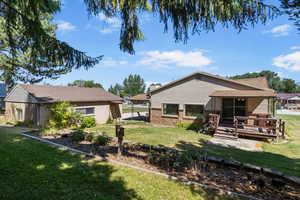 Rear view of property featuring a yard, brick siding, and a deck