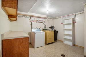 Washroom with washer and dryer, a textured ceiling, and light flooring