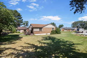 Rear view of property with brick siding and a lawn