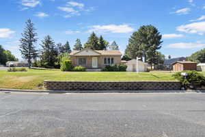 Ranch-style house featuring an outbuilding, a garage, a front yard, and brick siding