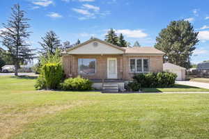 View of front of house with brick siding, a front lawn, and a detached garage
